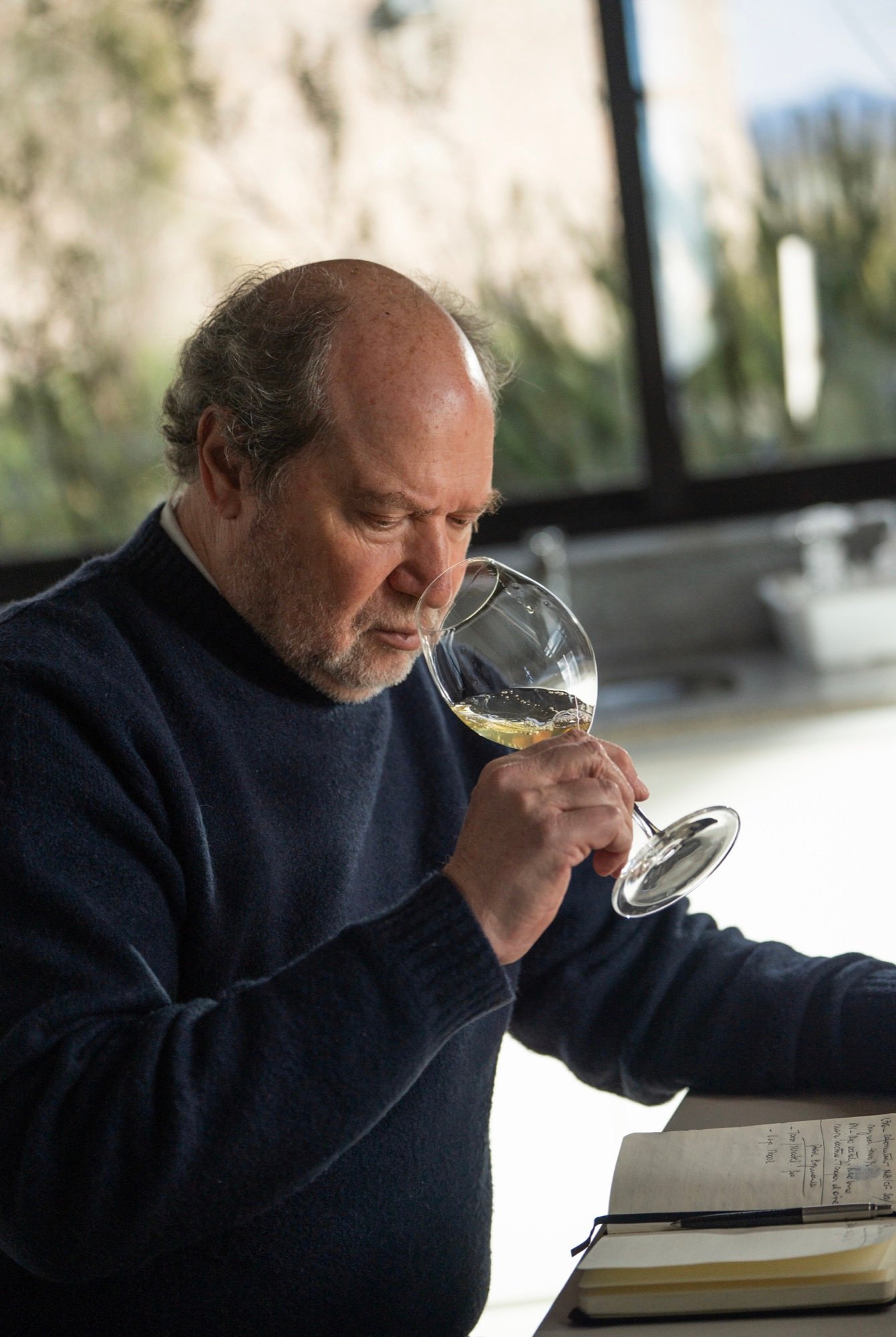 Daniel Pi oliendo una copa de vino blanco junto a sus notas de cata